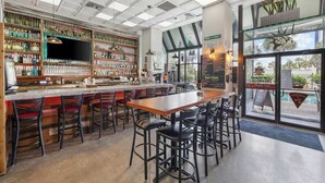A bar area with a long counter, multiple stools, and a variety of bottles and glasses on shelves. - Flip-Flop Hideaway 1BR (Myrtle Beach)