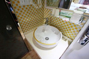 A bathroom with a checkered yellow and white tile wall, a white sink with a floral design, and a mirror above the sink. - Fujimengge Hotel Shanghai (Shanghai)