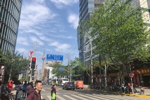 A busy urban street with pedestrians, vehicles, and commercial buildings. - Fujimengge Hotel Shanghai (Shanghai)