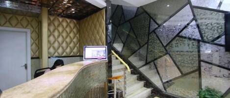 A reception area with a curved counter, a staircase with glass panels, and a door in the background.