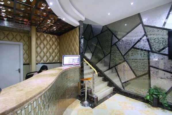 A reception area with a curved counter, a staircase with glass panels, and a door in the background.