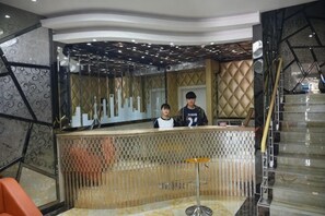 A reception area with a counter, a child, and a staircase. - Fujimengge Hotel Shanghai (Shanghai)