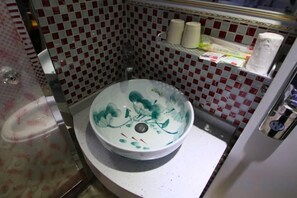 Une salle de bain avec un lavabo blanc, une douche et un mur à carreaux rouges et blancs.