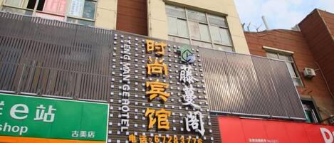 A building with multiple signs, including one for a hotel and another for a shop.