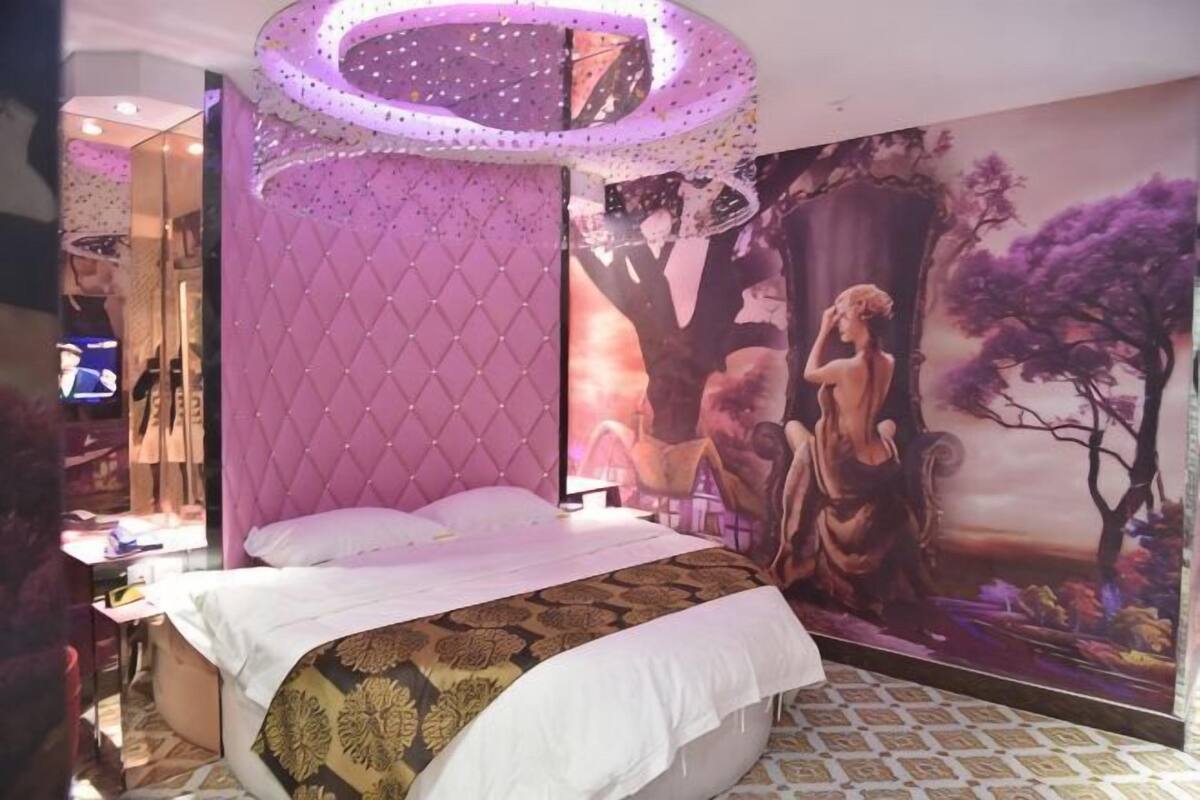 A bedroom with a bed, a large wall mural, and a ceiling light fixture.