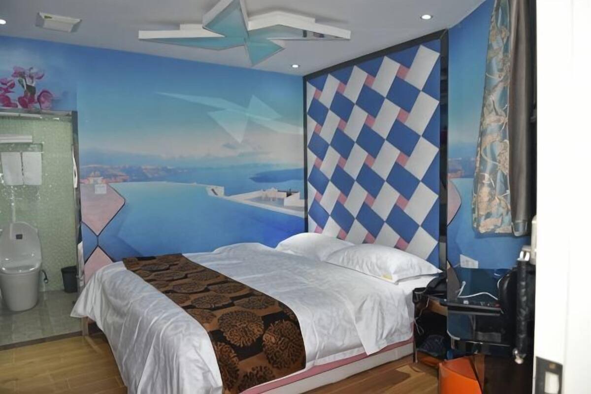 A hotel room with a bed, a desk, and a view of the sea.