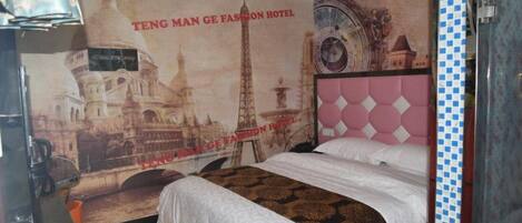 A hotel room with a bed, a poster of a cityscape, and a patterned carpet.