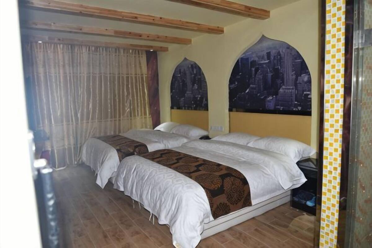 A hotel room with two beds, a cityscape mural, wooden beams, and a curtain.