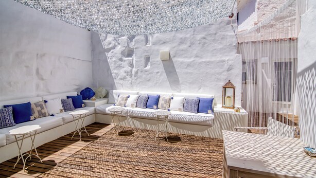 A modern, white interior with a patterned floor, a white sofa with blue cushions, and a small table with a lantern. - Ca s'Arader (Ciutadella de Menorca)