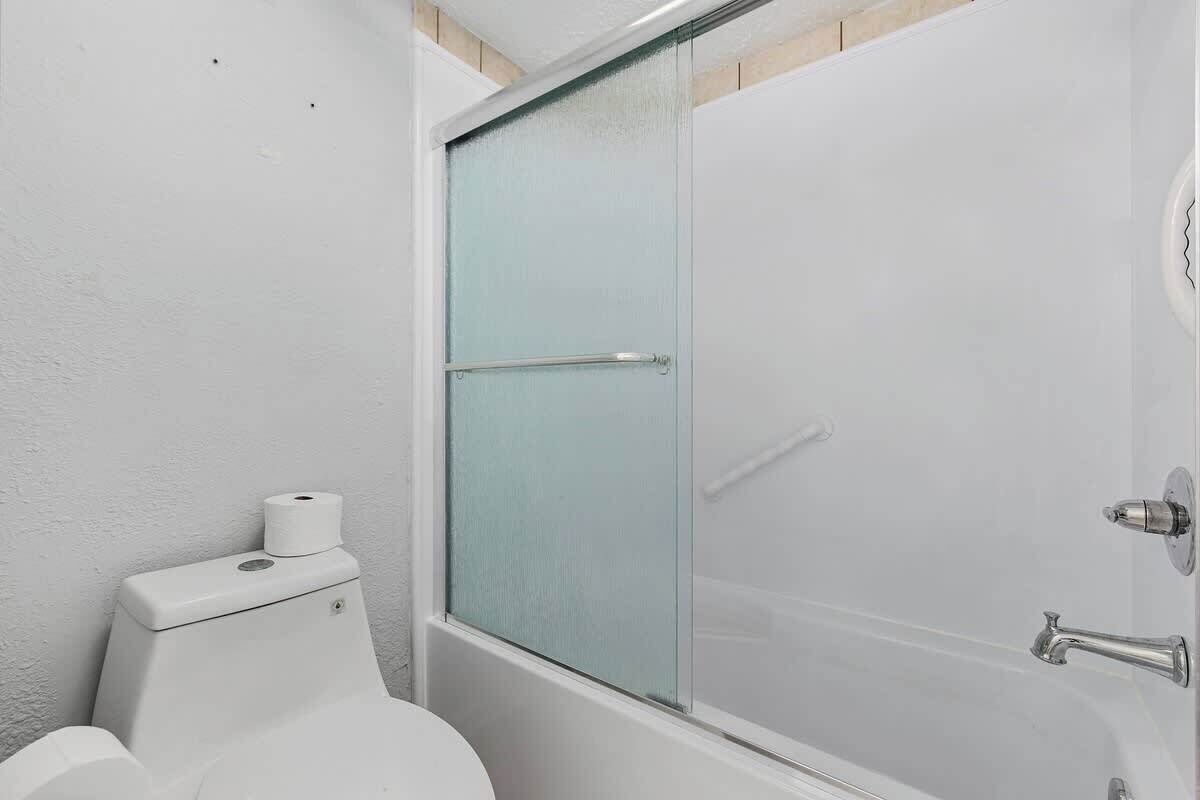 A bathroom with a toilet, a glass shower enclosure, and a bathtub.