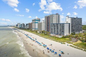 A coastal hotel with multiple high-rise buildings, a beach with umbrellas, and a clear view of the ocean. - Hight Floor Ocean View Condo (Myrtle Beach)