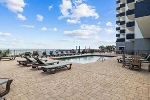 A poolside area with lounge chairs and a view of the ocean. - Hight Floor Ocean View Condo (Myrtle Beach)