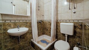 Ein Badezimmer mit Dusche, Waschbecken, Toilette und Spiegel.