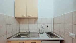 A compact kitchen with a sink, stove, and cabinets. - Apartments Pezo - Studio  ( Tina 3) (Baška Voda)
