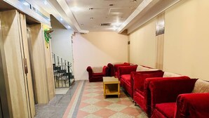 A hotel lobby with a checkered floor, red sofas, a wooden sideboard, and a staircase leading to an upper level. - Queens Valley Hotel (Luxor Governorate)