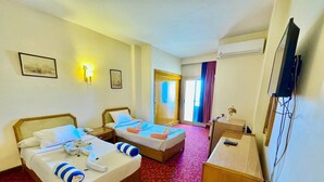 A hotel room with two beds, a desk, a TV, and a window with curtains. - Queens Valley Hotel (Luxor Governorate)