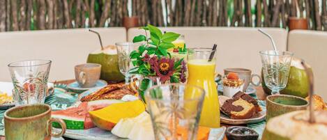 Un bufé de desayuno con diferentes alimentos y bebidas, con palmeras de fondo.