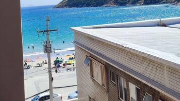 Un balcon donnant sur une plage et un bâtiment avec un toit en tuiles.
