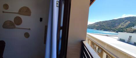 A balcony with a view of the sea and hills, a door, and wall decorations.