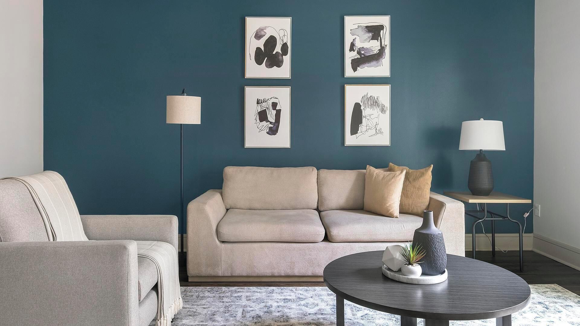 Un salon avec un mur d’accent de couleur turquoise, un canapé beige, une table basse ronde et un lampadaire.