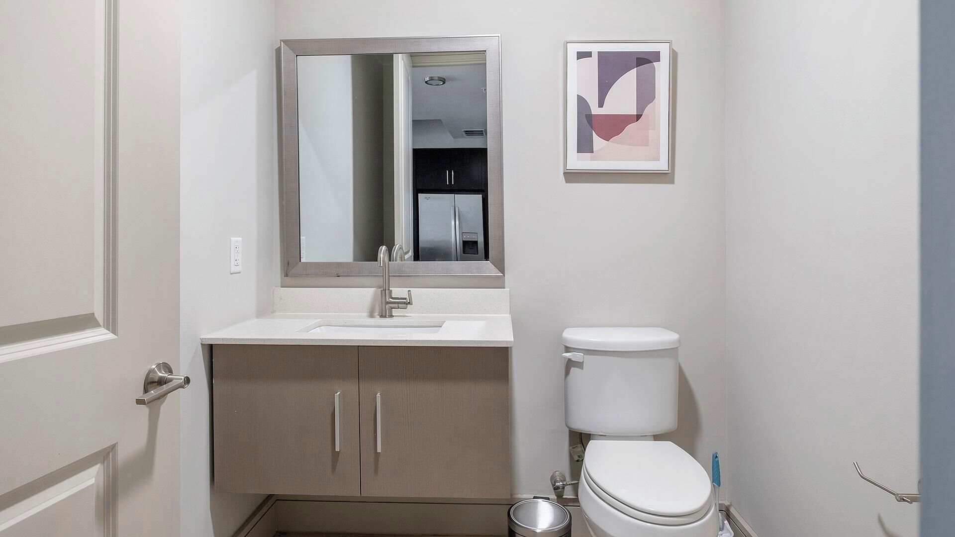 Une petite salle de bain avec un lavabo blanc, un miroir, des toilettes et un meuble de rangement.