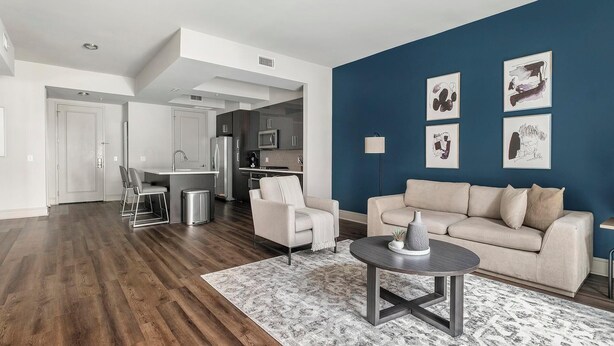 A modern living room with a dark blue accent wall, a beige sofa, and a round coffee table.