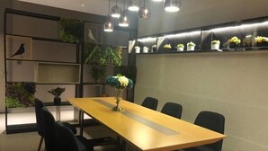 A conference room with a long table, black chairs, and a decorative vase. - Homeinn · neo (Qufu Jingxuan Middle Road Sankong) (Qufu)