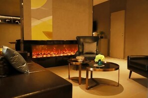 A modern living room with a fireplace, leather sofas, and a round coffee table. - Homeinn · neo (Qufu Jingxuan Middle Road Sankong) (Qufu)