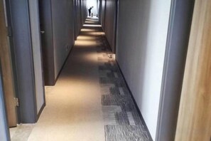 Un couloir dont le sol est recouvert de moquette et où l’on trouve des portes de part et d’autre.