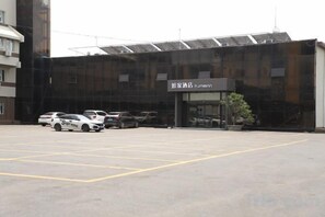 Un estacionamiento con varios autos, un edificio con un letrero que dice 'Hotel Inn' y un diseño arquitectónico moderno.