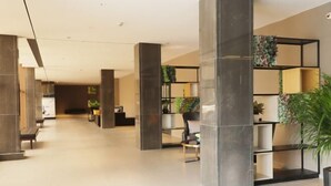 A spacious lobby with high ceilings, large pillars, and modern shelving units with plants. - Homeinn · neo (Qufu Jingxuan Middle Road Sankong) (Qufu)