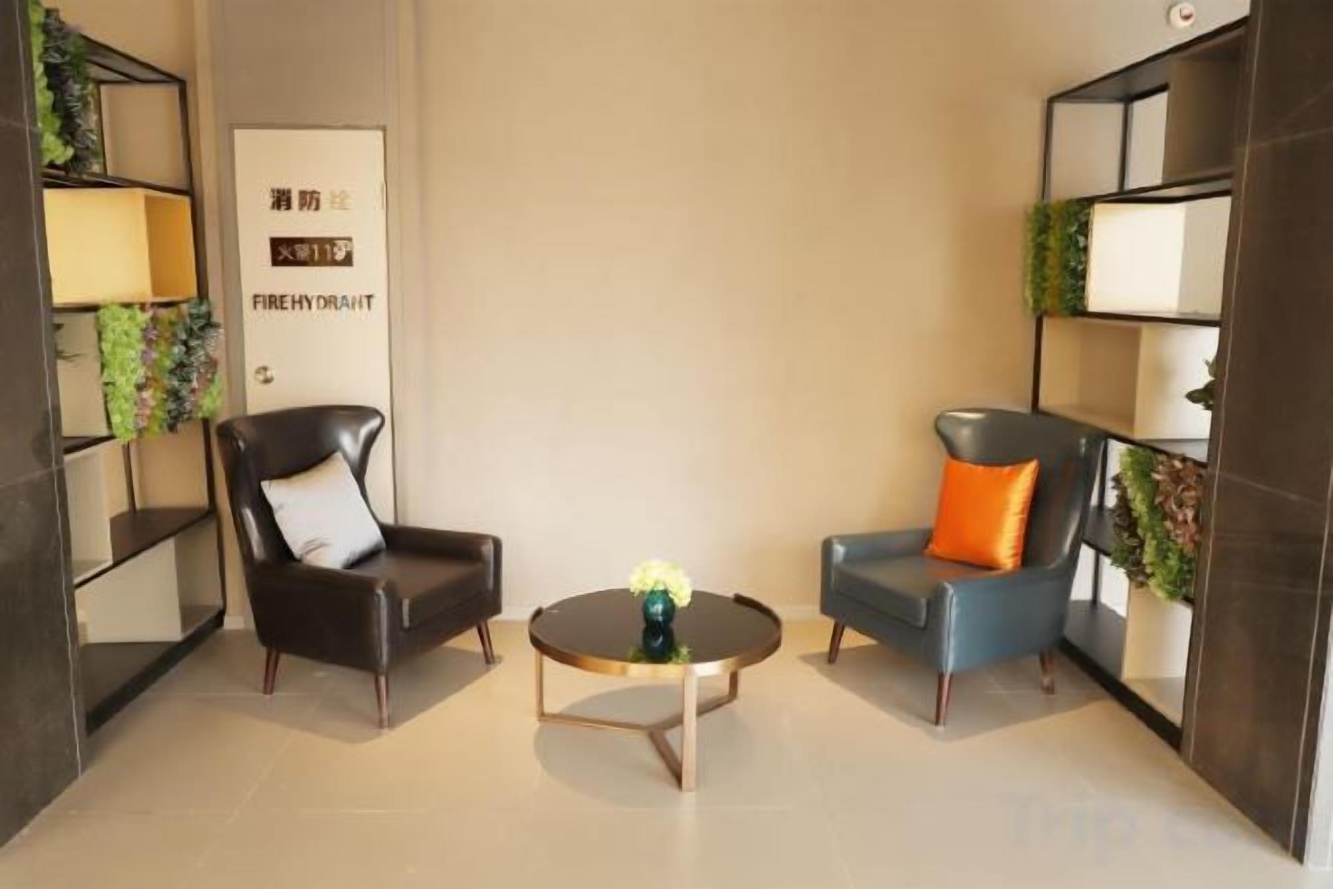 A room with two chairs, a coffee table, and shelves with plants.