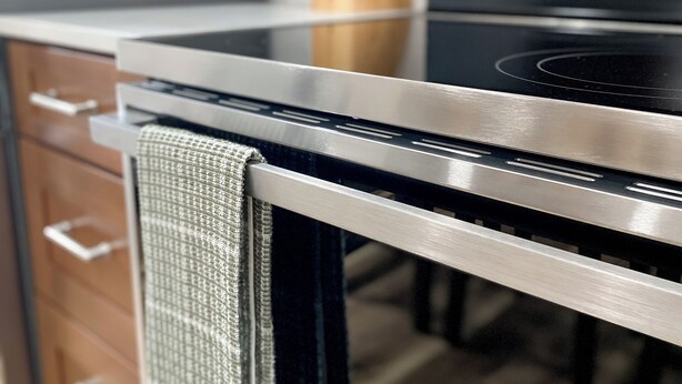 A kitchen with a stainless steel stove, wooden cabinets, and a wooden utensil holder.