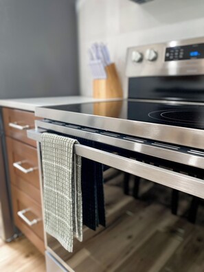 Uma cozinha com fogão de aço inoxidável, armários de madeira e porta-utensílios de madeira.