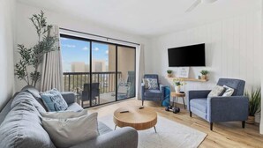 A modern living room with a sofa, armchairs, a coffee table, a TV, and a balcony with a city view. - The Coral Cove in Myrtle Beach (Myrtle Beach)