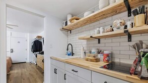 A modern kitchen with wooden shelves, a countertop, and a sink. - The Coral Cove in Myrtle Beach (Myrtle Beach)