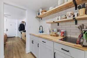 Uma cozinha moderna com prateleiras de madeira, bancada e pia.