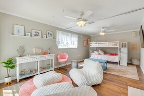 Habitación infantil con literas, un escritorio, una silla y un ventanal grande.