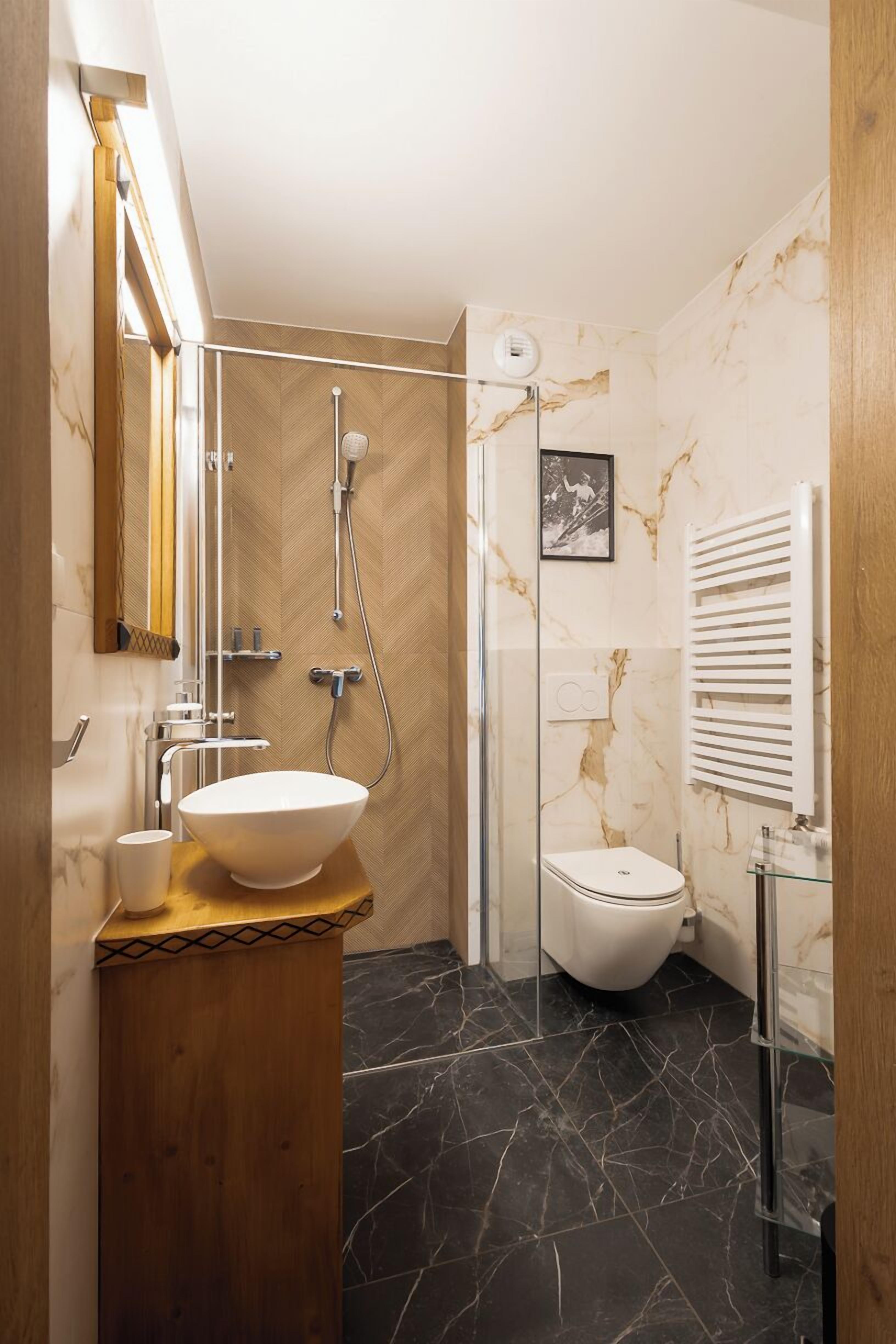 A modern bathroom with a marble vanity, a glass shower enclosure, and a white toilet.
