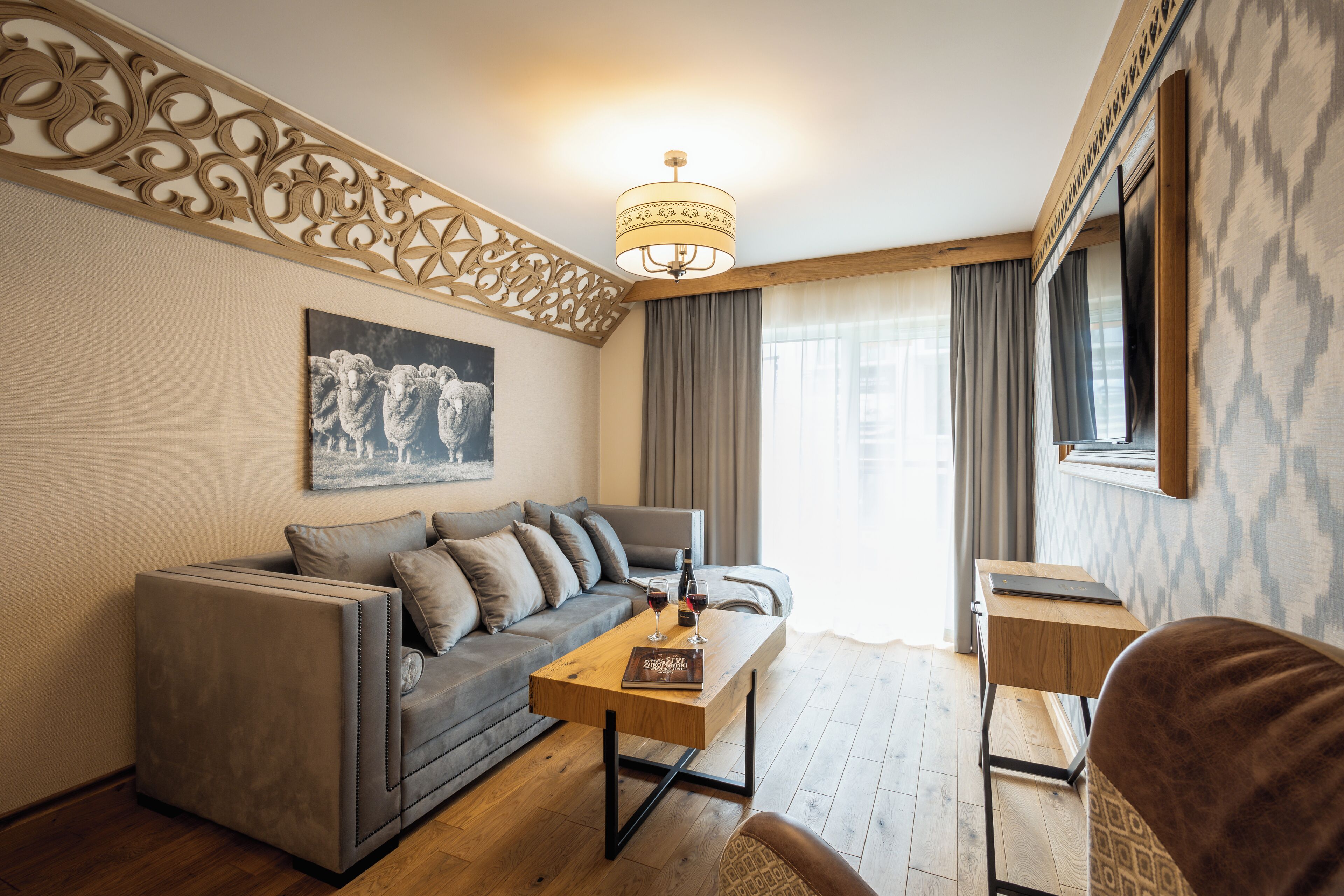 A modern living room with a grey sofa, a wooden coffee table, and a patterned wall.