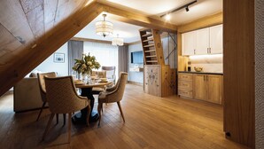 A dining area with a wooden ceiling, a staircase, and a kitchen with wooden cabinets. - Aparthotel Merynos (Zakopane)