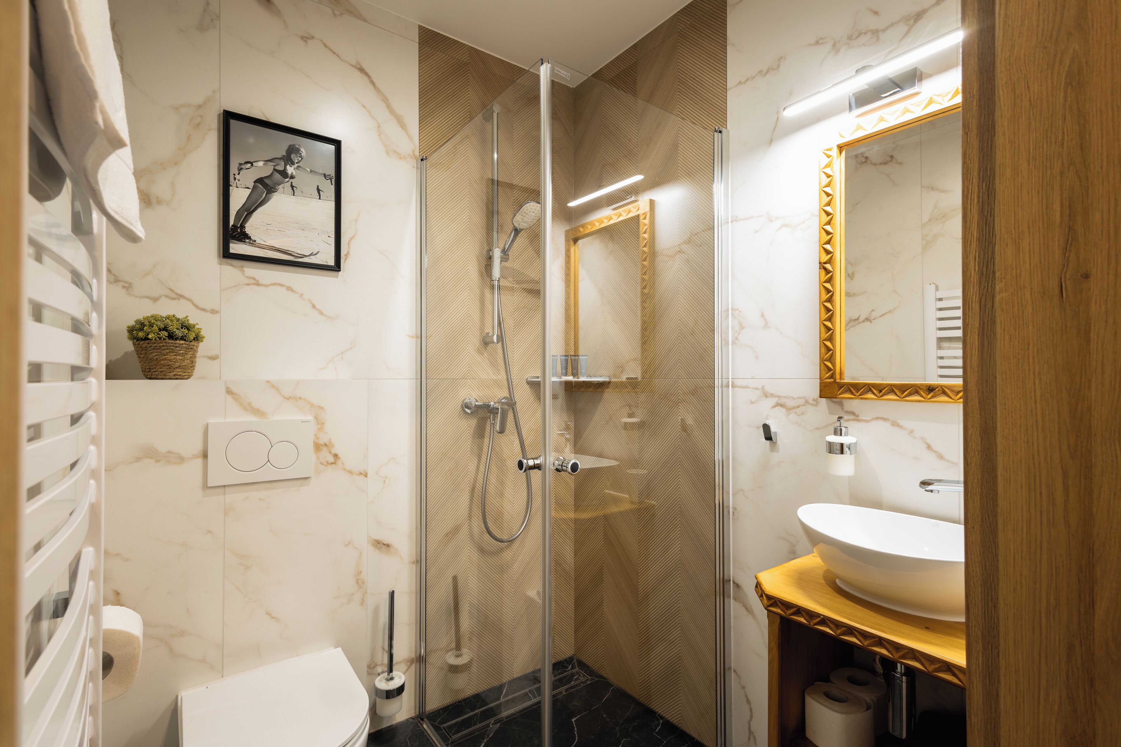 Un baño moderno con ducha de vidrio, lavamanos blanco y pared de mármol.