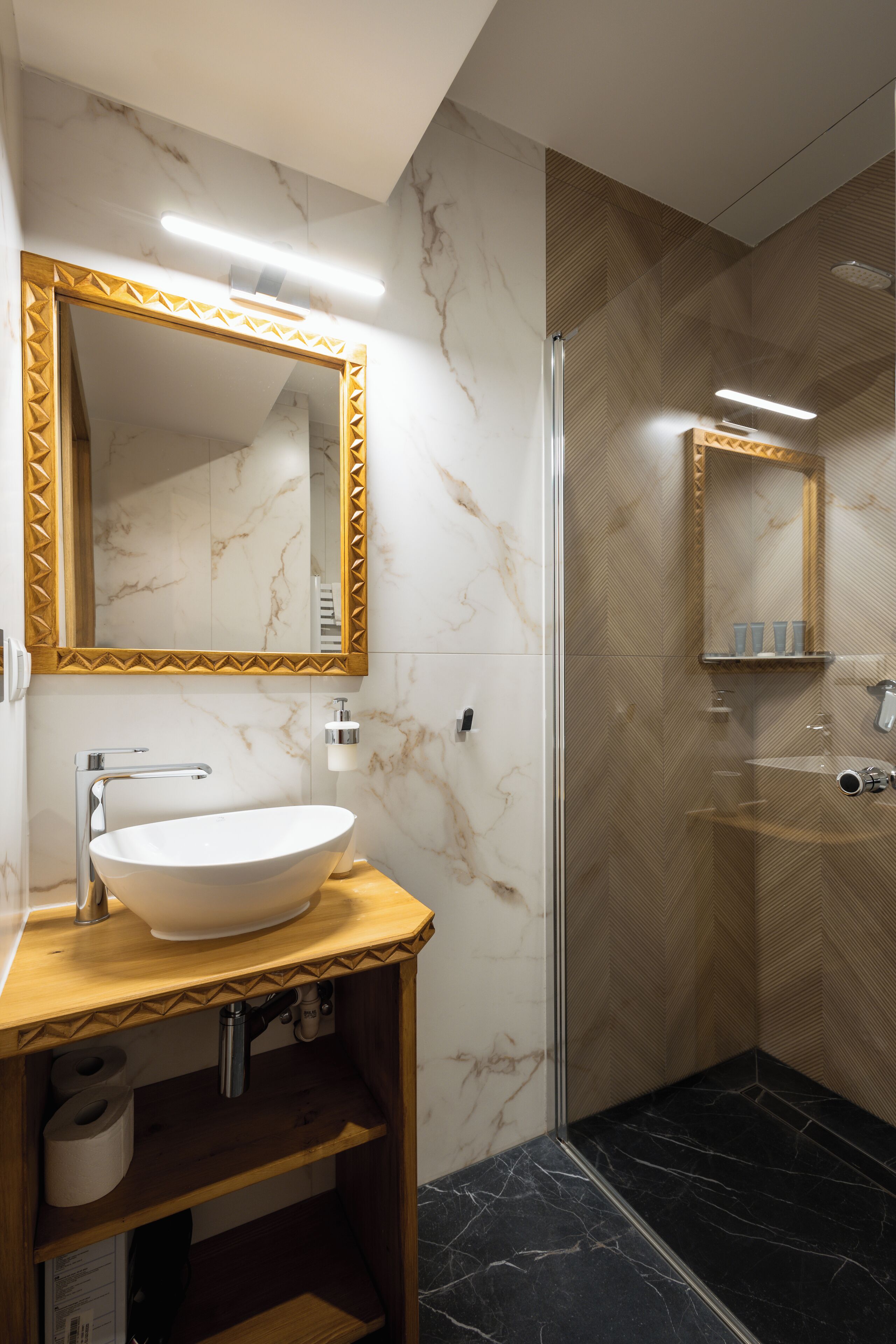 Une salle de bain moderne avec un meuble-lavabo en marbre, un grand miroir, une cabine de douche et un sol carrelé en marbre.