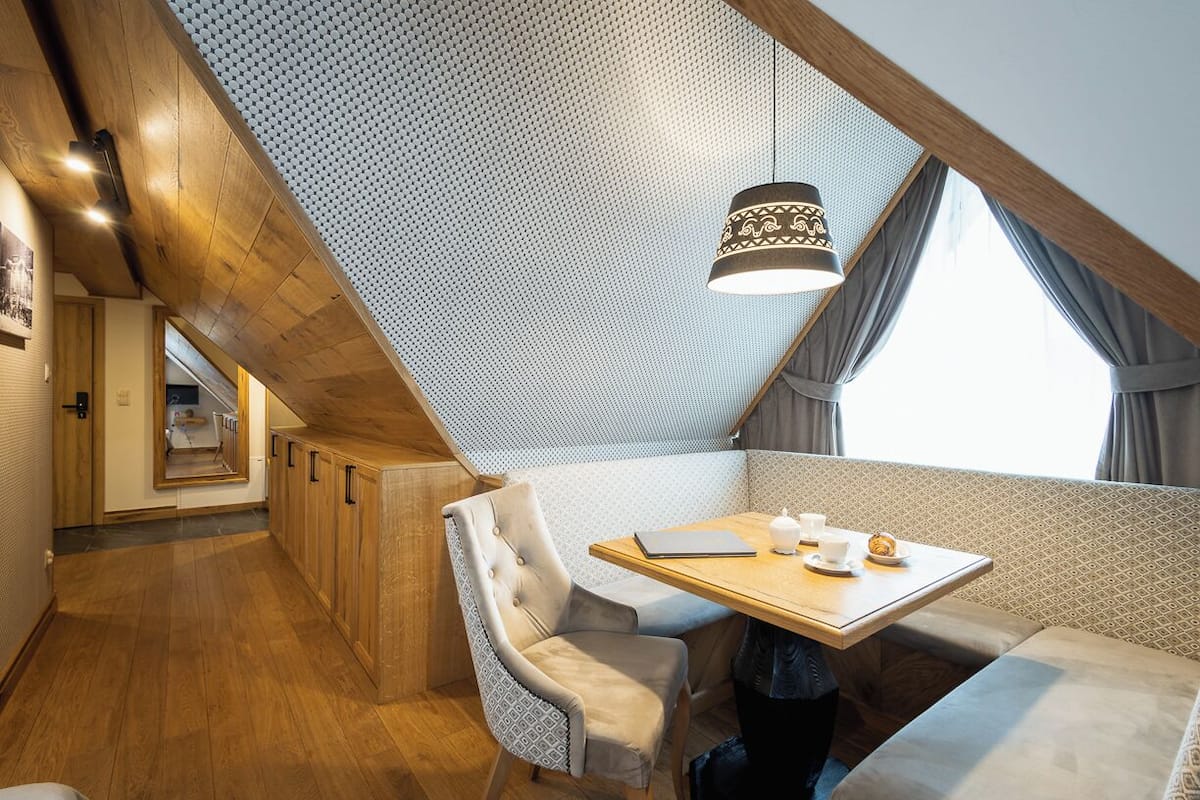 A cozy dining area with a wooden table, cushioned seating, and a patterned ceiling.