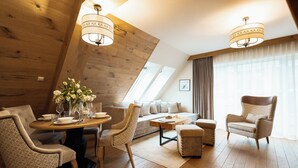 A modern living room with a wooden ceiling, a round dining table, and a sofa. - Aparthotel Merynos (Zakopane)