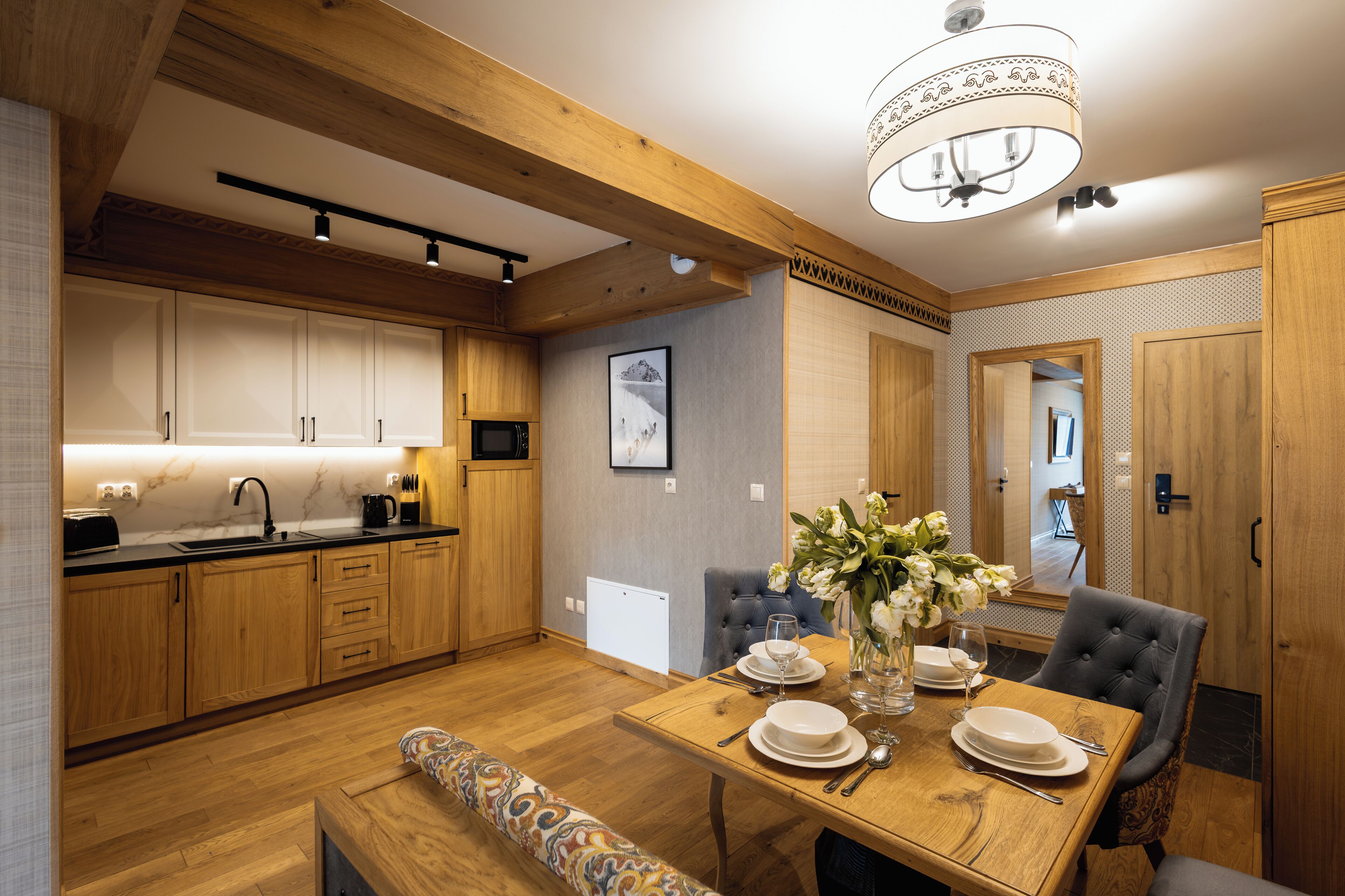 A modern kitchen with wooden cabinets, a dining table set for four, and a bench.