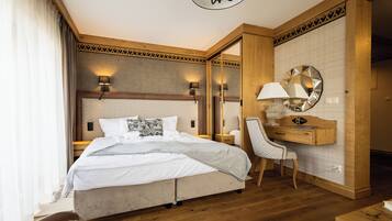 A hotel room with a large bed, a desk, a chair, and a mirror.