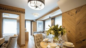 A hotel room with a dining area featuring a round table set for four, a sofa, and a bed. - Aparthotel Merynos (Zakopane)