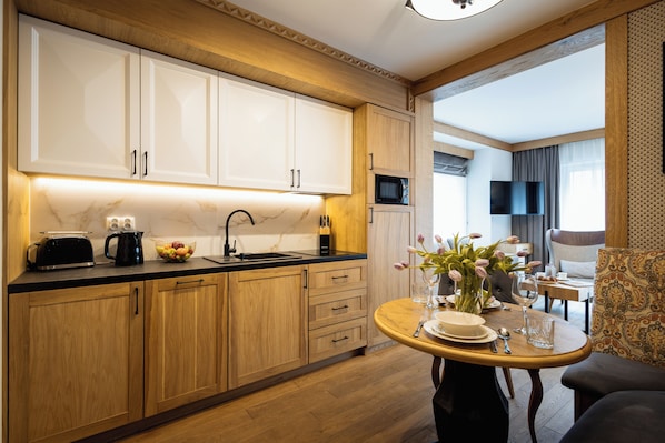 Una cocina moderna con armarios de madera, encimera negra y comedor con mesa preparada para dos.