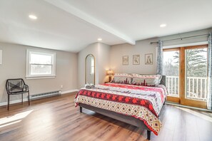 A bedroom with a large bed, a chair, a window, and a door leading to a balcony. - Fire Pit + Game Room: Spacious Poconos Retreat! (Long Pond)
